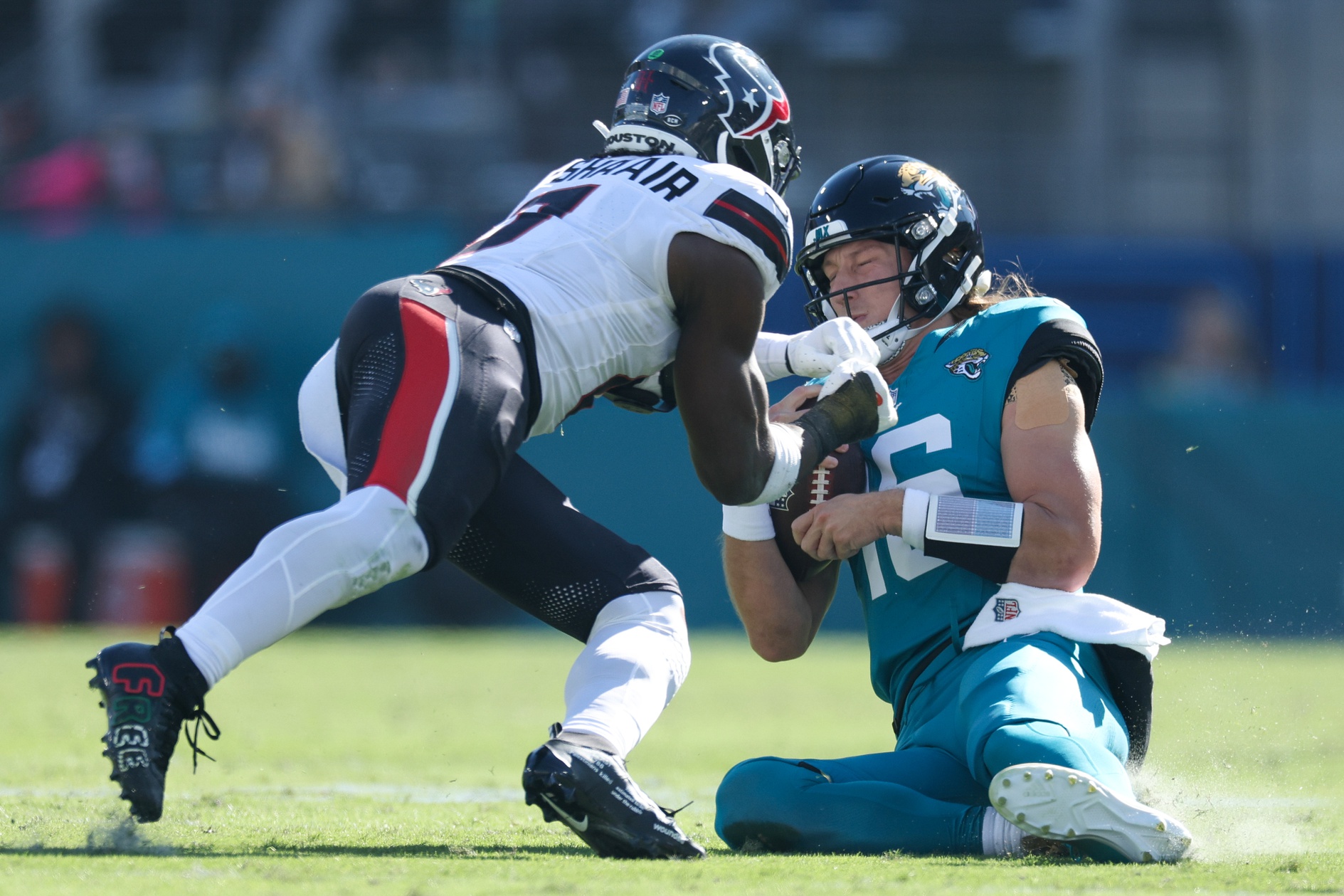 Dec 1, 2024; Jacksonville, Florida, USA; Jacksonville Jaguars quarterback Trevor Lawrence (16) slides down in front of Houston Texans linebacker Azeez Al-Shaair (0) in the second quarter in the second quarter at EverBank Stadium.