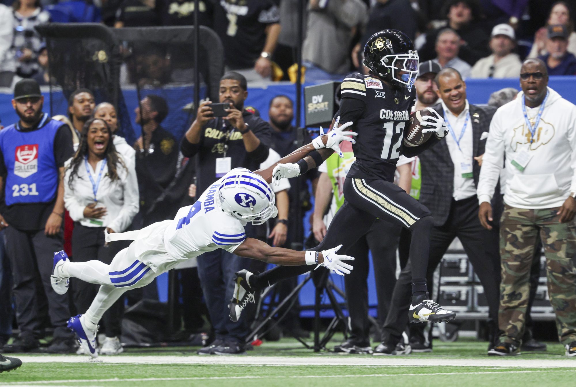 Dec 28, 2024; San Antonio, TX, USA; Colorado Buffaloes wide receiver Travis Hunter (12) runs with the ball as Brigham Young Cougars cornerback Mory Bamba (4) attempts to make a tackle during the second quarter at Alamodome.