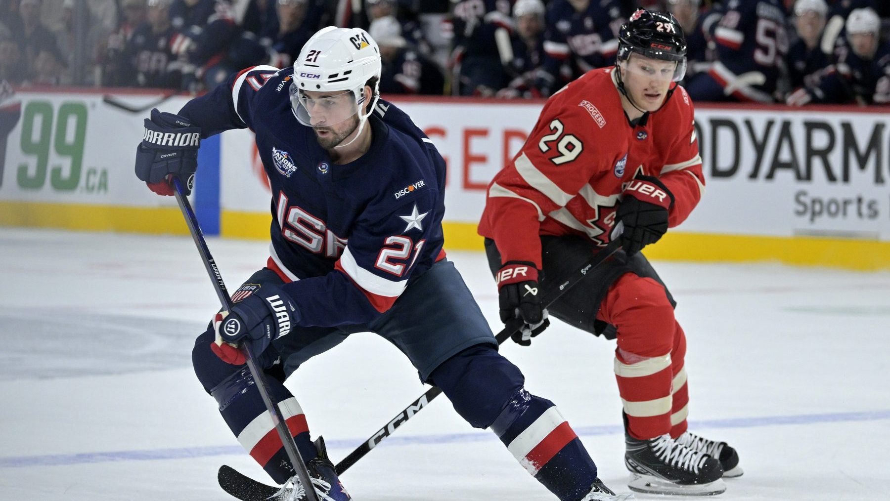 Feb 15, 2025; Montreal, Quebec, CAN; [Imagn Images direct customers only] Team United States forward Dylan Larkin (21) plays the puck and Team Canada forward Nathan MacKinnon (29) defends in the first period during a 4 Nations Face-Off ice hockey game at the Bell Centre