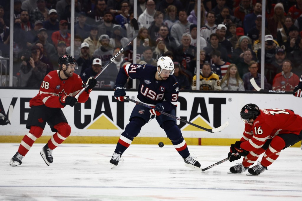 Feb 20, 2025; Boston, MA, USA; [Imagn Images direct customers only] Team USA forward Auston Matthews (34) plays the puck against Team Canada forward Brandon Hagel (38) and forward Mitch Marner (16) during the first period during the 4 Nations Face-Off ice hockey championship game at TD Garden.