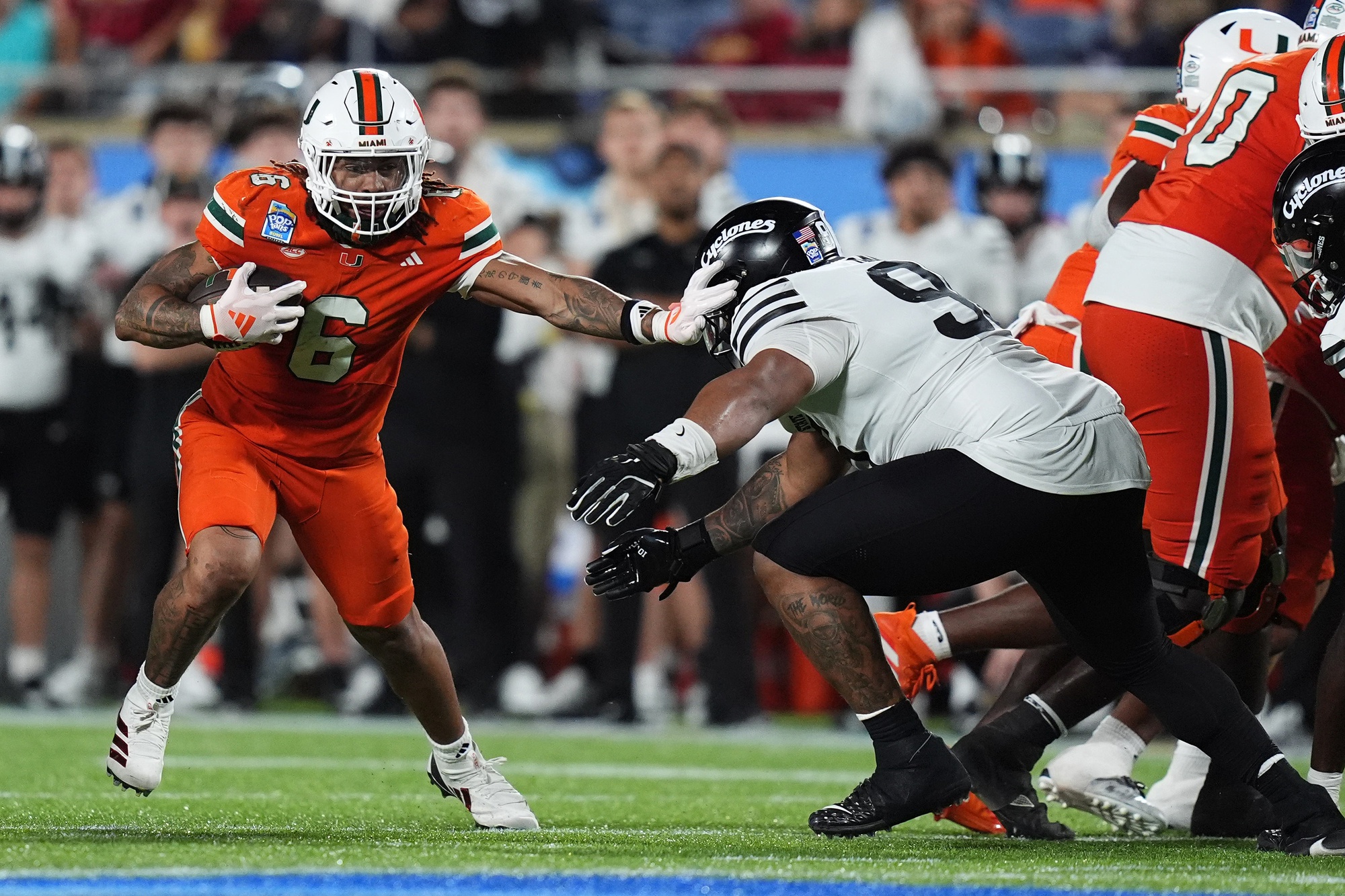 Dec 28, 2024; Orlando, FL, USA; Miami Hurricanes running back Damien Martinez (6) stiff arms Iowa State Cyclones linebacker Cael Brezina (9) during the second half at Camping World Stadium.