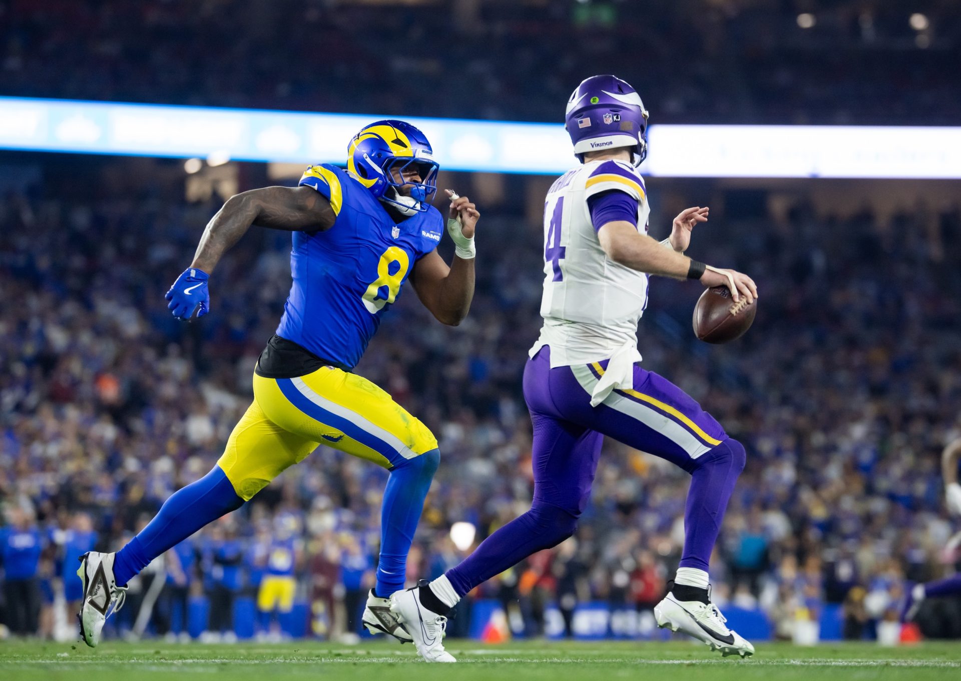 Jan 13, 2025; Glendale, AZ, USA; Minnesota Vikings quarterback Sam Darnold (14) is pursued by Los Angeles Rams linebacker Jared Verse (8) during an NFC wild card game at State Farm Stadium.