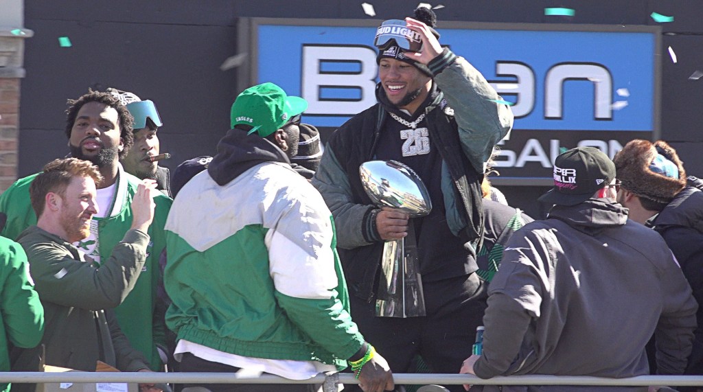 Eagles running back Saquon Barkley, center, holds the Vince Lombardi trophy during the Eagles Super Bowl championship parade on Friday, Feb. 14, 2025.