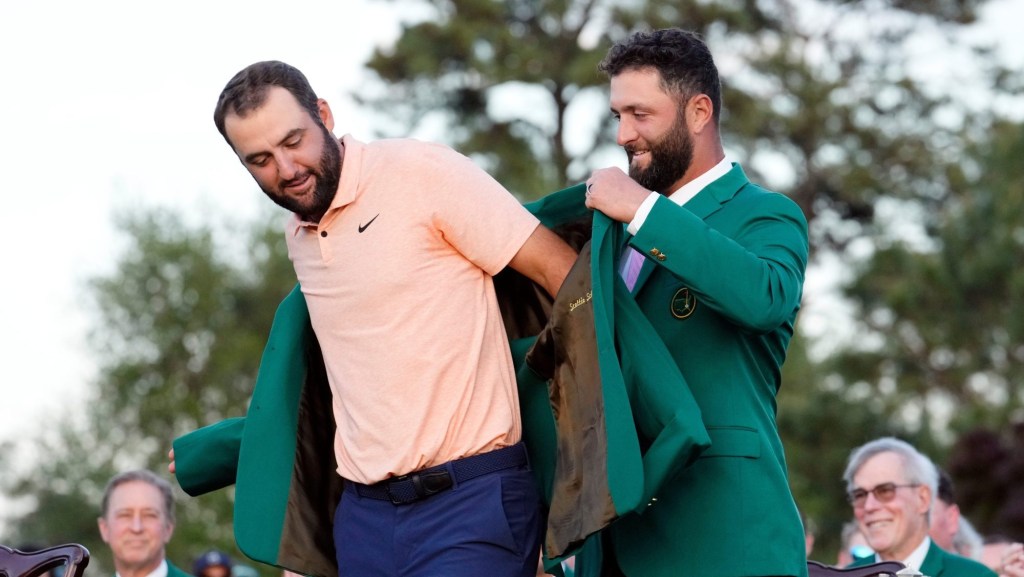 Apr 14, 2024; Augusta, Georgia, USA; 2023 Masters champion Jon Rahm places the green jacket on 2024 Masters champion Scottie Scheffler during the green jacket ceremony following the final round of the Masters Tournament.