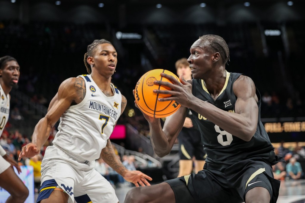 Mar 12, 2025; Kansas City, MO, USA; Colorado Buffaloes forward Bangot Dak (8) drives to the basket around West Virginia Mountaineers guard Javon Small (7) during the second half at T-Mobile Center.