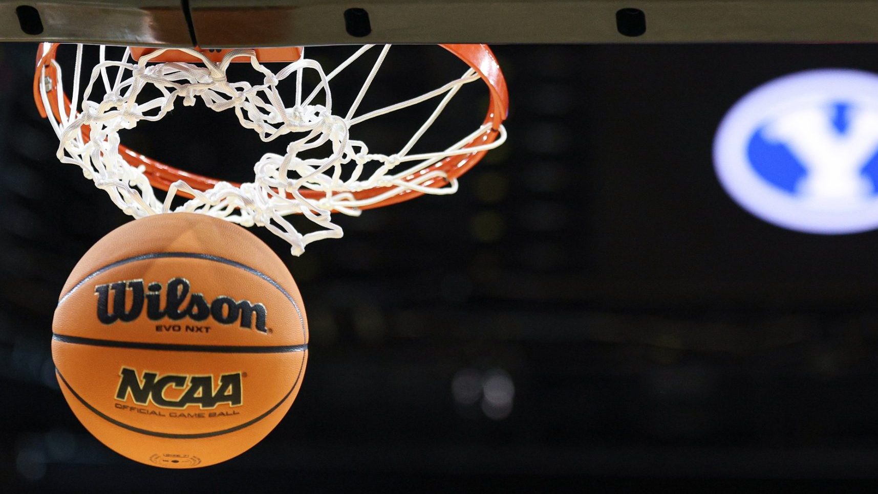 Mar 26, 2025; Newark, NJ, USA; An NCAA Wilson official game ball passes thorough a basket in front of an Brigham Young Cougars logo during a practice sessions in preparation for an East Regional semifinal games at Prudential Center