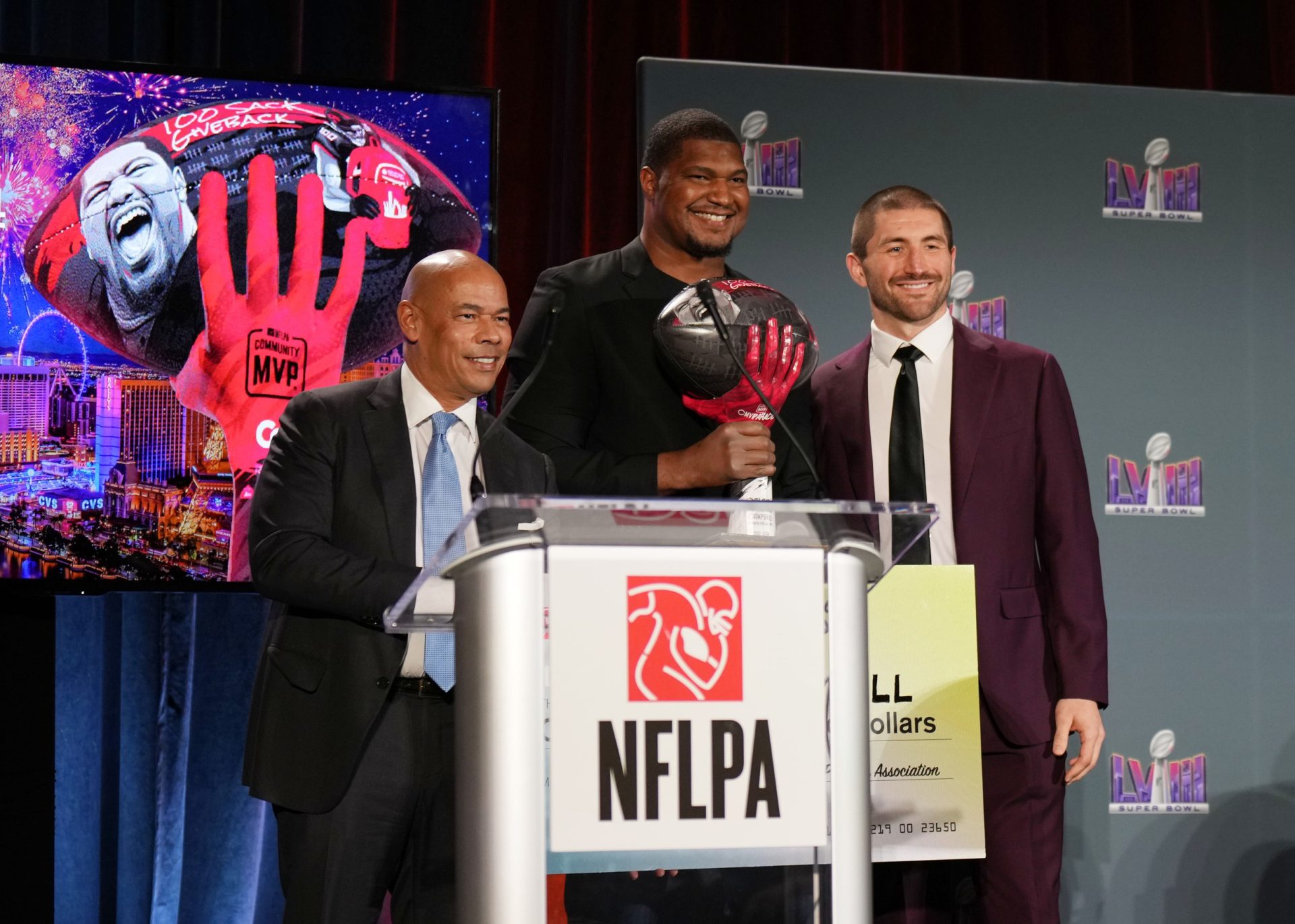 Feb 7, 2024; Las Vegas, NV, USA; Calais Campbell (middle) receives the NFLPA Alan Page Community Award from executive director Lloyd Howell (left) and president) JC Tretter (right) at the NFLPA Press Conference at the Mandalay Bay Convention Center prior to Super Bowl LVIII.