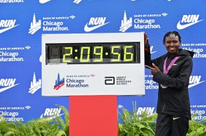 Oct 13, 2024; Chicago, IL, USA; Ruth Chepngetich of Kenya poses for a photo with the time clock after finishing first in the womens race, setting a new world record at 2:09:56 during the Chicago Marathon at Grant Park.