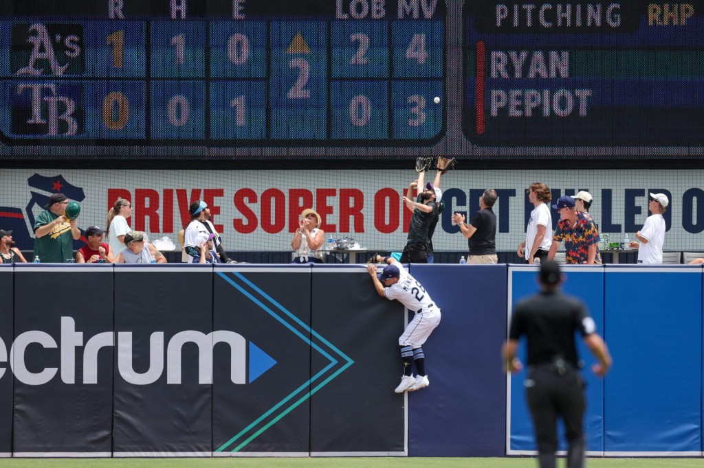 Jul 2, 2025; Tampa, Florida, USA; Tampa Bay Rays left fielder Jake Mangum (28) leaps for a ball over the wall against the Oakland Athletics in the second inning at George M. Steinbrenner Field.