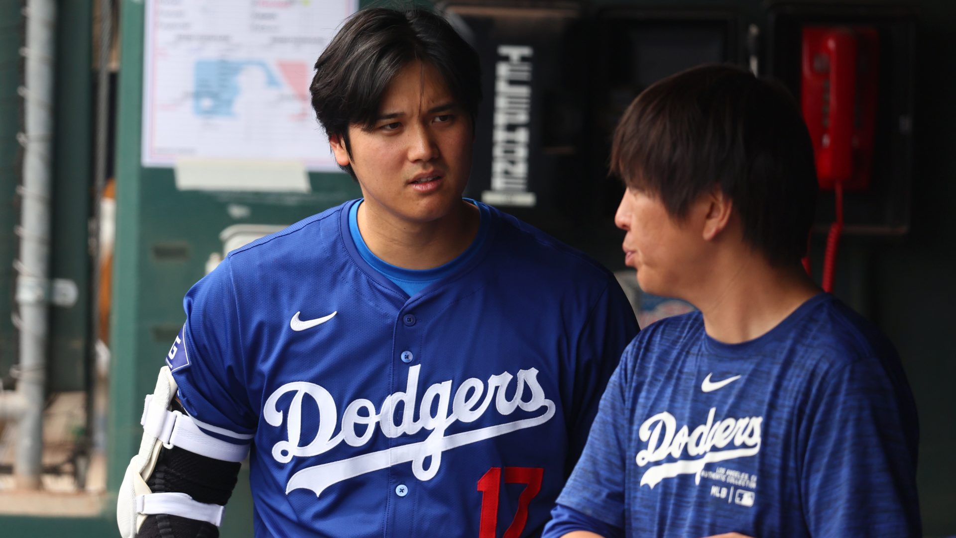 Mar 12, 2024; Phoenix, Arizona, USA; Los Angeles Dodgers designated hitter Shohei Ohtani talks with translator Ippei Mizuhara in the dugout against the San Francisco Giants during a spring training baseball game at Camelback Ranch-Glendale.