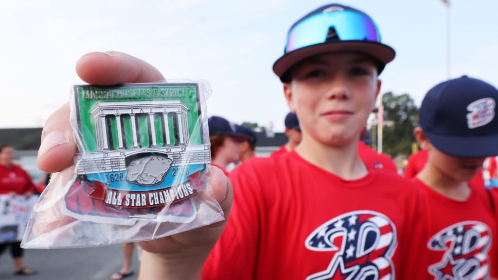 Bridgewater American 12U Little League player Micah Poulter holds a District 7 pin during a send-off rally to the New England regional tournament in Bristol, Connecticut, from Legion Field on Friday, August 2, 2024.