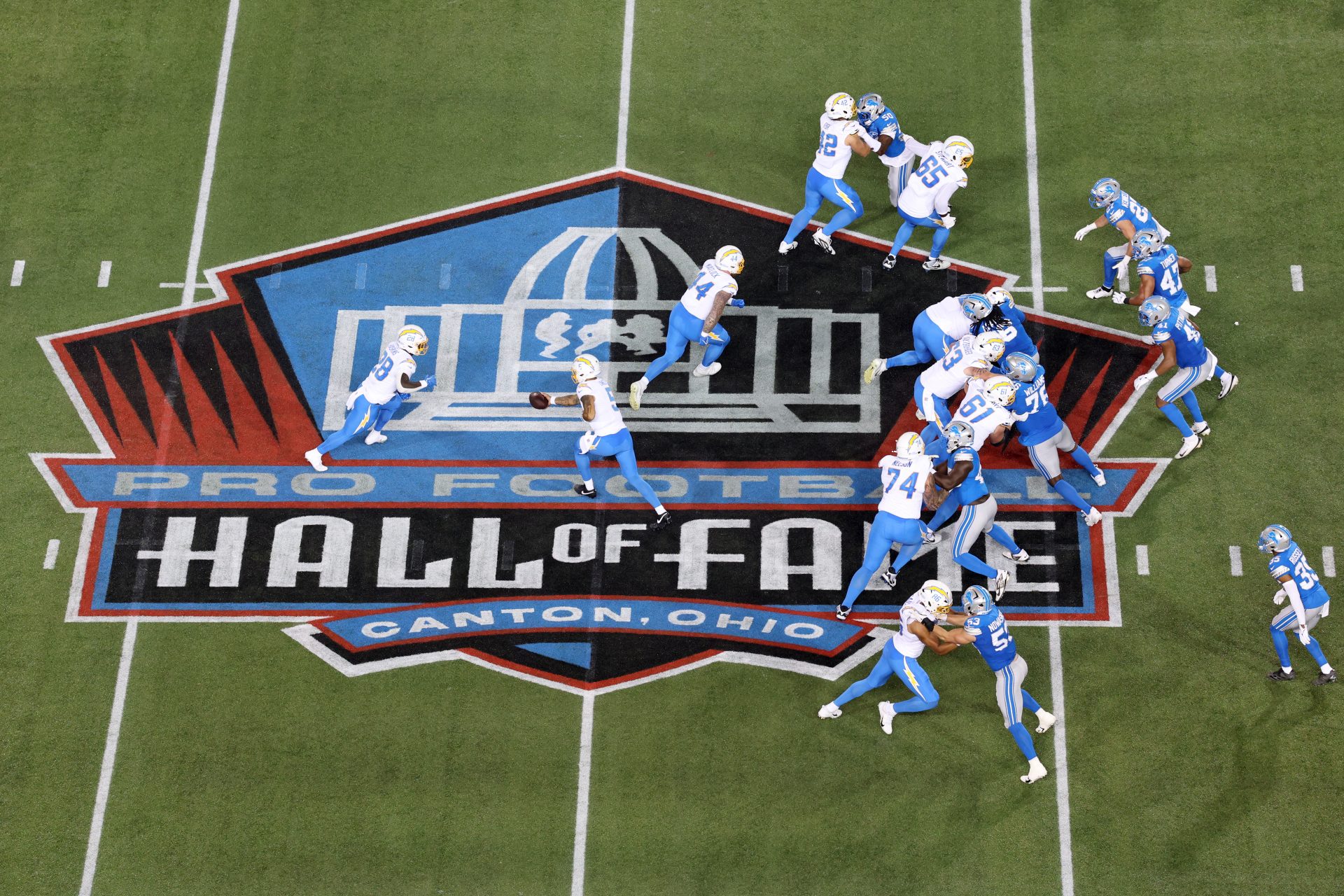 Jul 31, 2025; Canton, Ohio, USA; Los Angeles Chargers quarterback Trey Lance (5) hands off to running back Hassan Haskins (28) in the third quarter against the Detroit Lions at Tom Benson Hall of Fame Stadium.