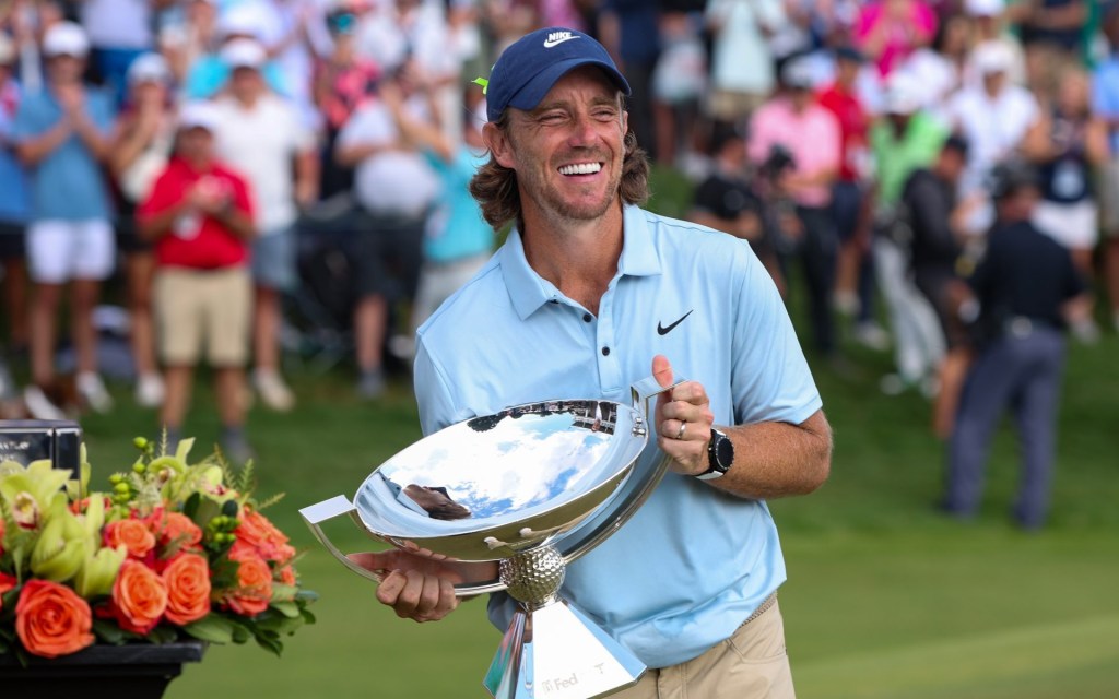 Aug 24, 2025; Atlanta, Georgia, USA; Tommy Fleetwood holds the FedExCup Trophy on the 18th green after winning the TOUR Championship golf tournament.