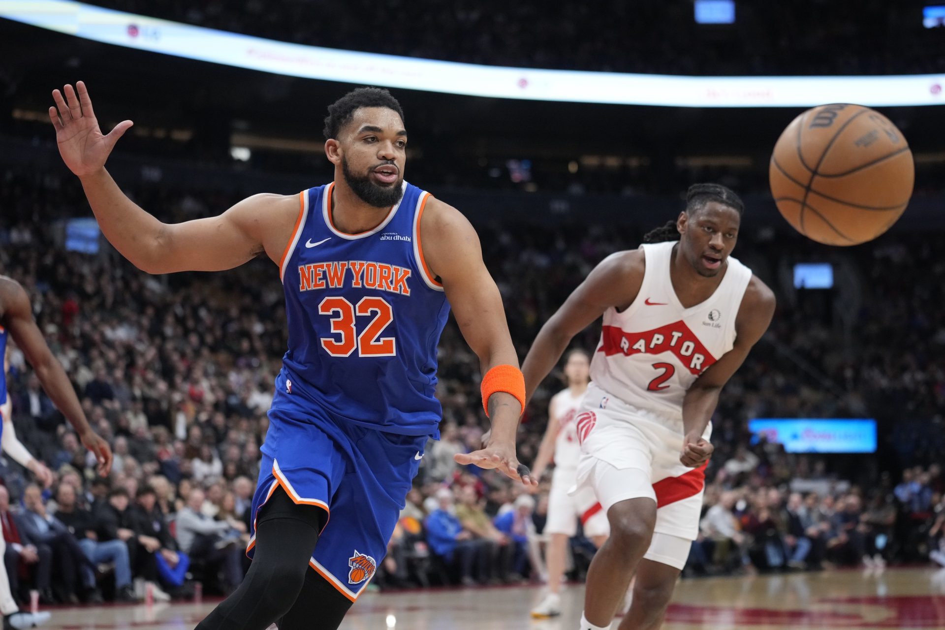 Feb 4, 2025; Toronto, Ontario, CAN; New York Knicks center Karl-Anthony Towns (32) and Toronto Raptors forward Jonathon Mogbo (2) chase after a loose ball during the second half at Scotiabank Arena.