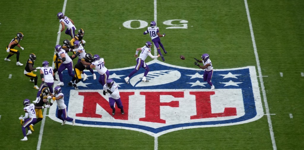 Sep 28, 2025; Dublin, Ireland; A general overall view as Minnesota Vikings quarterback Carson Wentz (11) pitches the ball to running back Jordan Mason (27) at midfield on the NFL shield logo against the Pittsburgh Steelers in the first quarter during an NFL International Series game at Croke Park