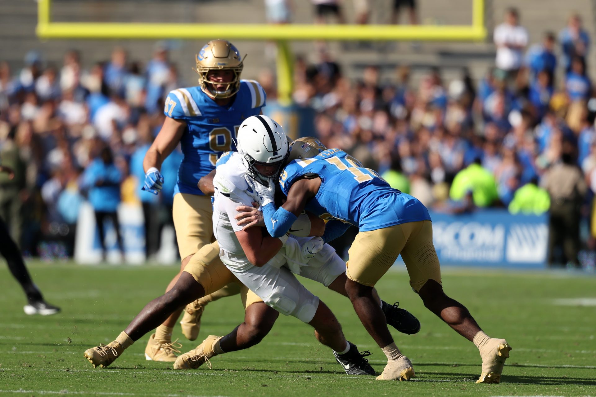 Oct 4, 2025; Pasadena, California, USA; Penn State Nittany Lions quarterback Drew Allar (15) takes hits from UCLA Bruins linebacker Jalen Woods (9) and defensive back Rodrick Pleasant (18) during the fourth quarter at Rose Bowl.