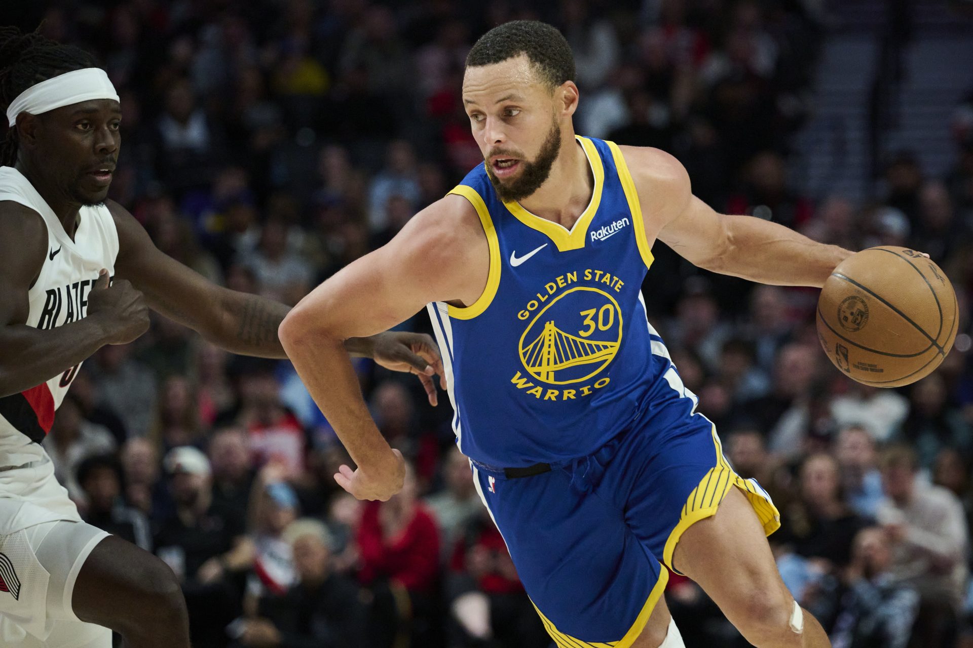 Oct 14, 2025; Portland, Oregon, USA; Golden State Warriors guard Stephen Curry (30) drives past Portland Trail Blazers guard Jrue Holiday (5) during the first half at Moda Center.