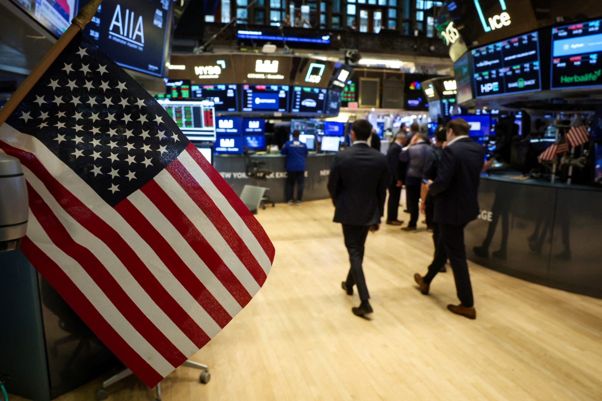 NYSE. A U.S. flag is displayed as traders work on the floor at the New York Stock Exchange (NYSE) in New York City, U.S., November 19, 2025.