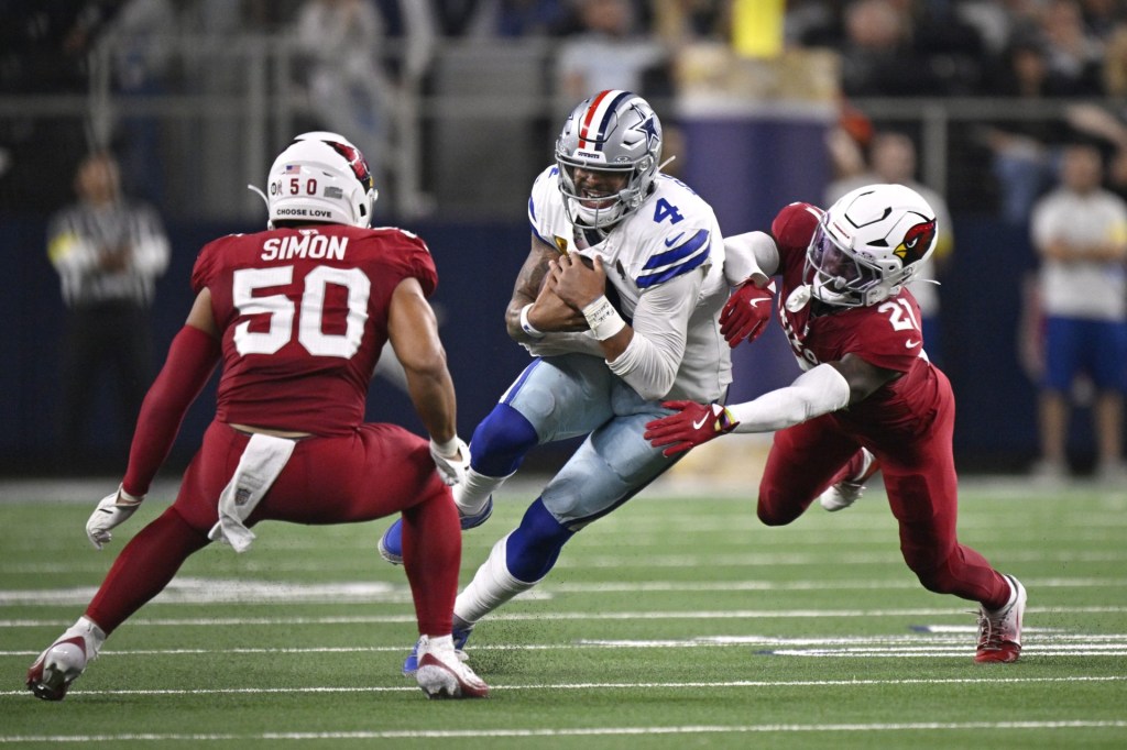 Nov 3, 2025; Arlington, Texas, USA; Dallas Cowboys quarterback Dak Prescott (4) runs against Arizona Cardinals cornerback Garrett Williams (21) and linebacker Cody Simon (50) in the second half at AT&T Stadium.