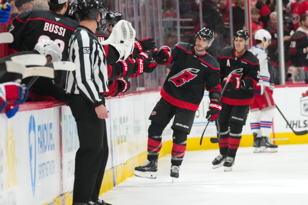 Nov 15, 2025; Raleigh, North Carolina, USA; Carolina Hurricanes defenseman Shayne Gostisbehere (4) celebrates with teammates after scoring a goal against the New York Rangers during the second period at Lenovo Center.