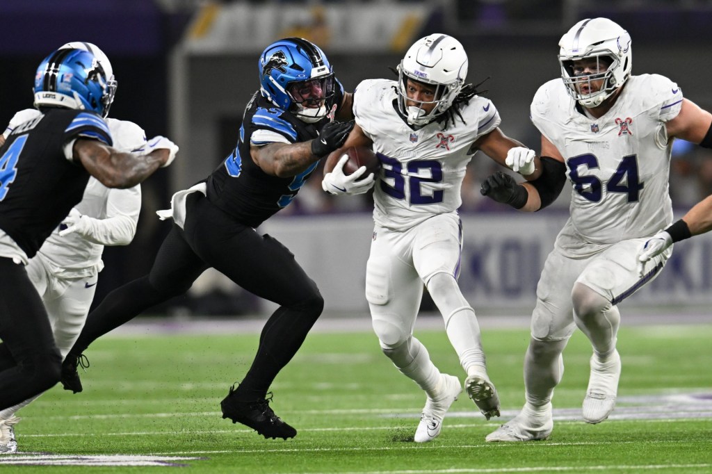 Dec 25, 2025; Minneapolis, Minnesota, USA; Minnesota Vikings running back Ty Chandler (32) carries the ball defended by Detroit Lions linebacker Derrick Barnes (55) in the second half at U.S. Bank Stadium.