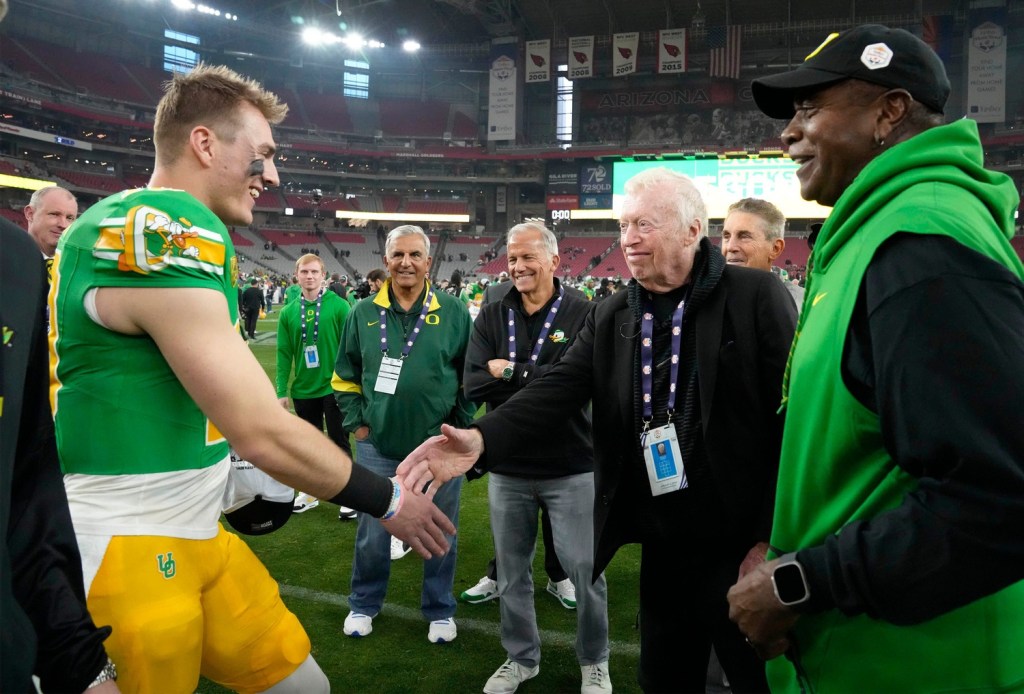 Oregon Ducks quarterback Bo Nix greets Phil Knight after defeating the Liberty Flames to win the Fiesta Bowl at State Farm Stadium in Glendale on Jan. 1, 2024.