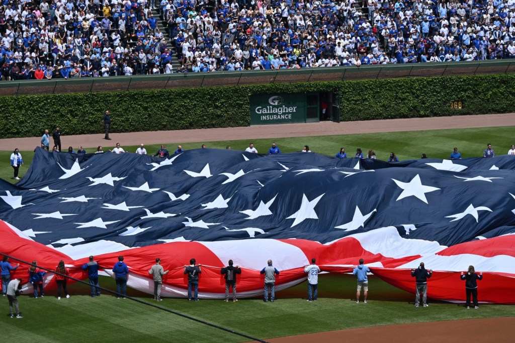May 26, 2025; Chicago, Illinois, USA; Flag holders unfold the American flag prior to a game between the Chicago Cubs and the Colorado Rockies at Wrigley Field.