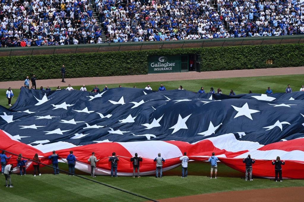 May 26, 2025; Chicago, Illinois, USA; Flag holders unfold the American flag prior to a game between the Chicago Cubs and the Colorado Rockies at Wrigley Field.