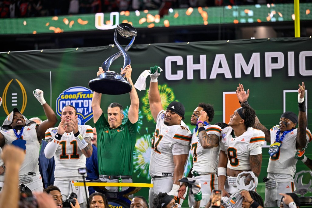 Dec 31, 2025; Arlington, TX, USA; Miami Hurricanes head coach Mario Cristobal hoists the trophy as he celebrates with his team after the 2025 Cotton Bowl and quarterfinal game of the College Football Playoff at AT&T Stadium.