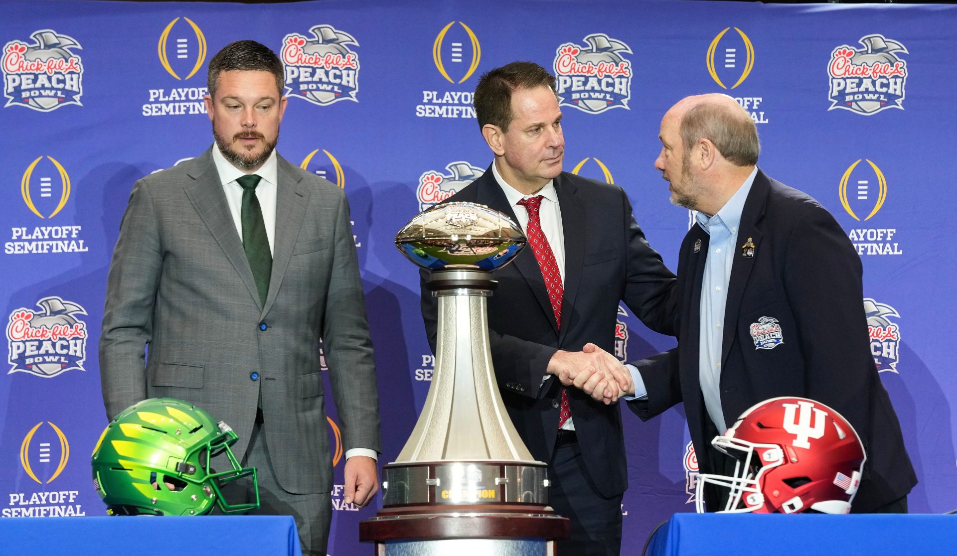 Oregon Ducks head coach Dan Lanning and Indiana Hoosiers head coach Curt Cignetti shake hands with Gary Stokan on Thursday, Jan. 8, 2026, during a coaches' press conference ahead of the College Football Playoff Peach Bowl game at the College Football Hall of Fame in Atlanta.