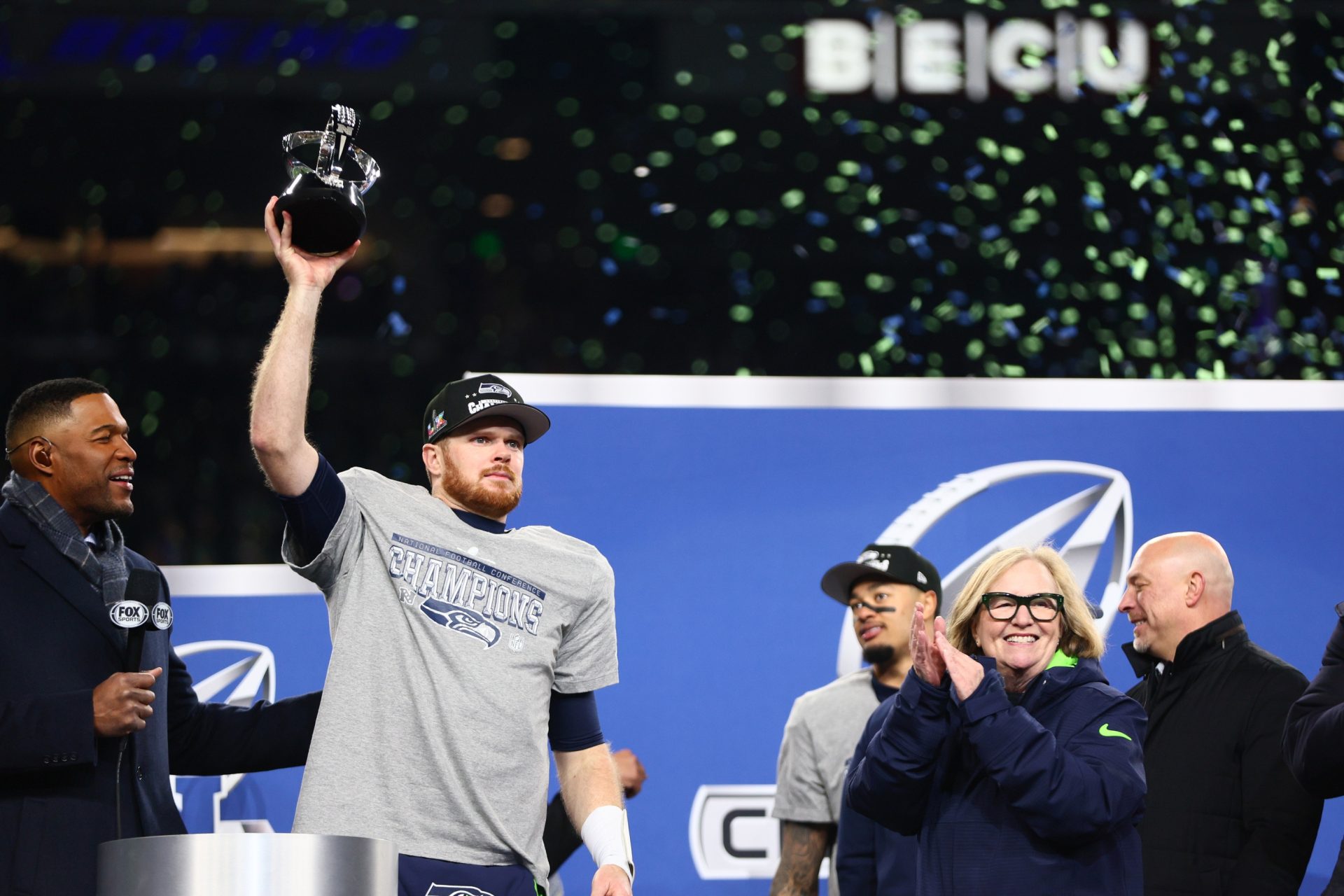 Jan 25, 2026; Seattle, WA, USA; Seattle Seahawks quarterback Sam Darnold (14) celebrates with the trophy on the podium after defeating the Los Angeles Rams in the 2026 NFC Championship Game at Lumen Field.
