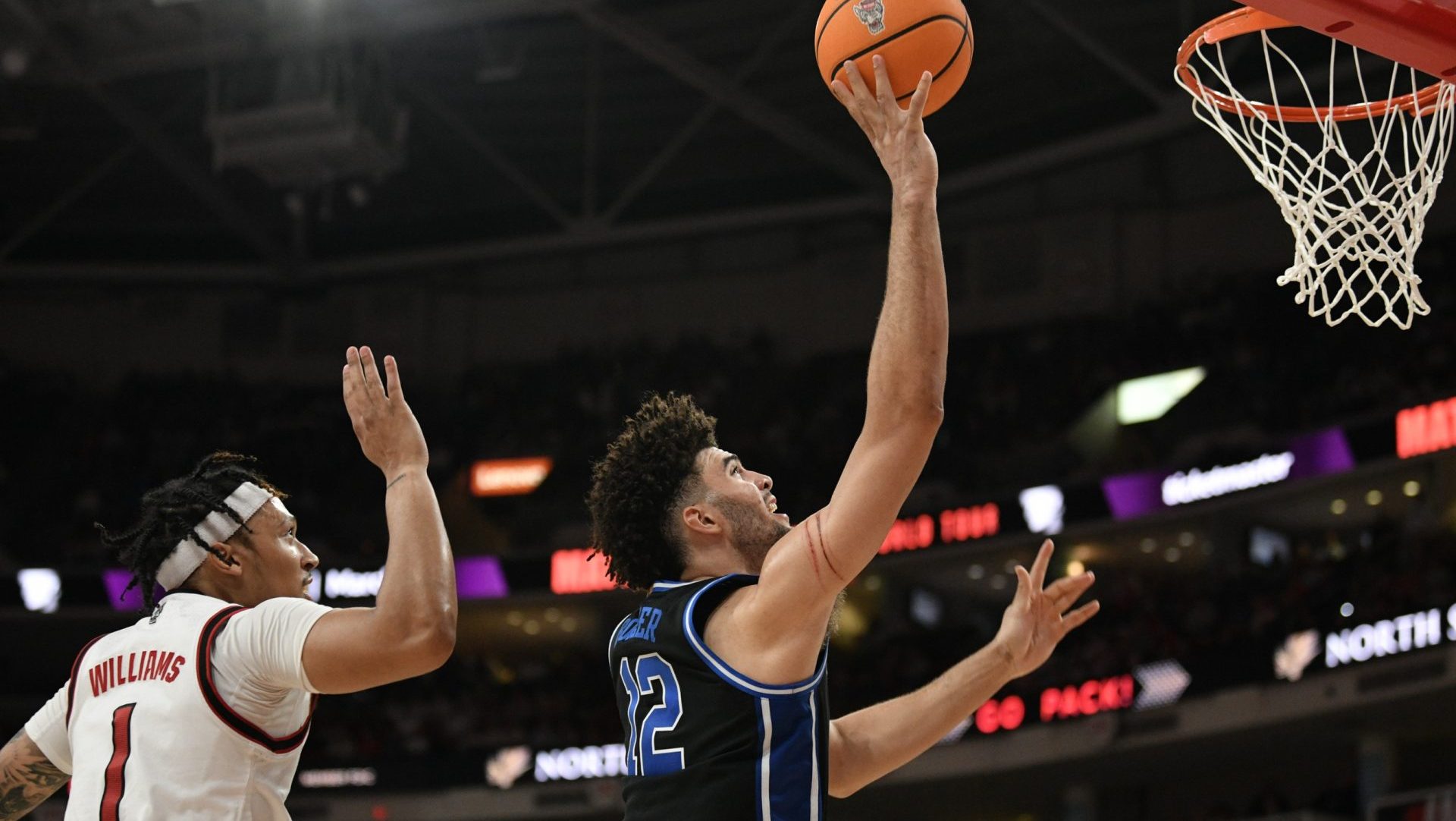Mar 2, 2026; Raleigh, North Carolina, USA; Duke Blue Devils forward Cameron Boozer (12) lays the ball up against NC State Wolfpack forward Darrion Williams (1) during the second half at Lenovo Center. Mandatory Credit: Zachary Taft-Imagn Images