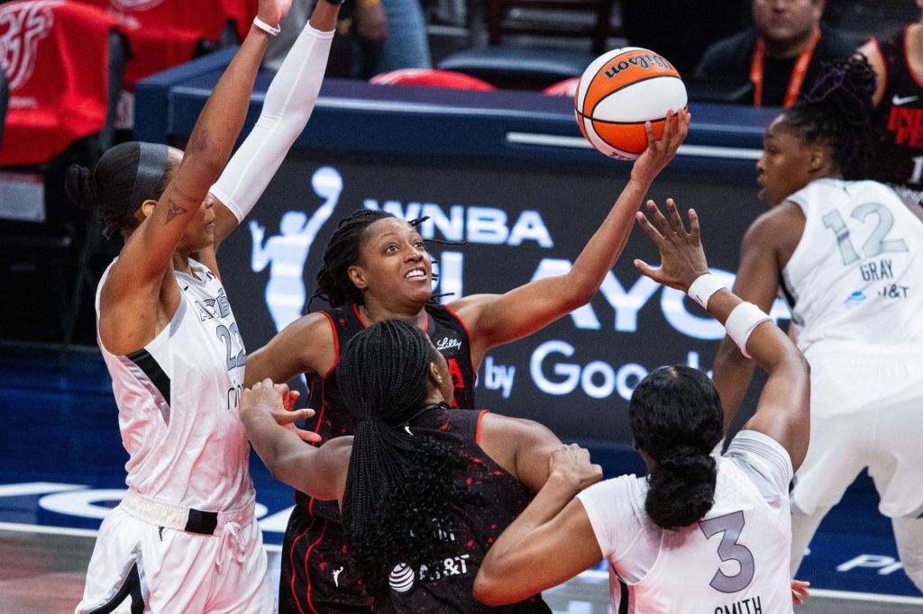 Sep 28, 2025; Indianapolis, Indiana, USA; Indiana Fever guard Kelsey Mitchell (0) shoots the ball while Las Vegas Aces forward NaLyssa Smith (3) defends in the first half during game four of the second round for the 2025 WNBA Playoffs at Gainbridge Fieldhouse.