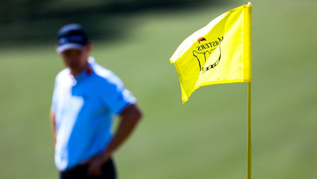 Apr 9, 2026; Augusta, Georgia, USA; The Masters flag stick blows in the wind as Justin Rose surveys the ninth green in the background during the first round of the Masters Tournament at Augusta National Golf Club. Mandatory Credit: Bill Streicher-Imagn Images