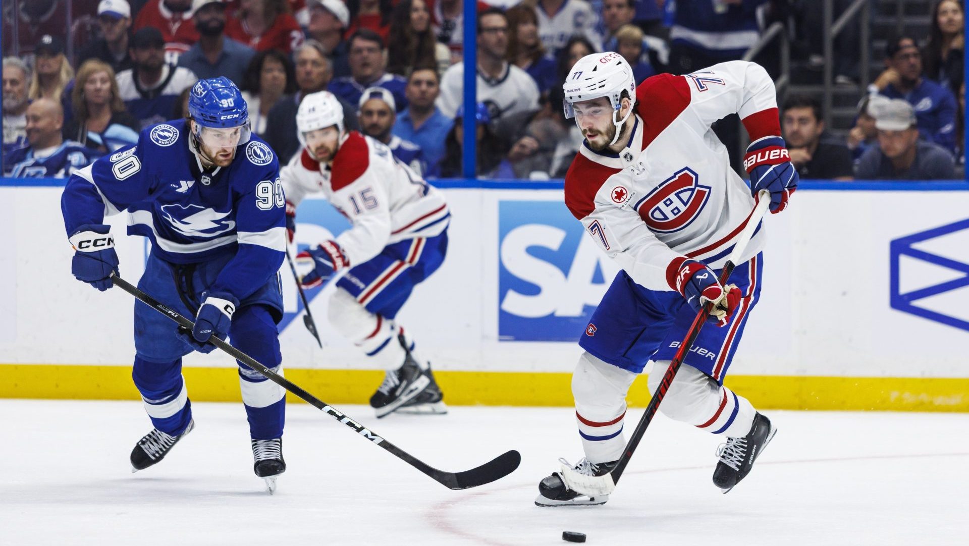 May 3, 2026; Tampa, Florida, USA; Tampa Bay Lightning defenseman J.J. Moser (90) and Montreal Canadiens forward Kirby Dach (77) chase the puck during the third period in game seven of the first round of the 2026 Stanley Cup Playoffs at Benchmark International Arena. Mandatory Credit: Morgan Tencza-Imagn Images