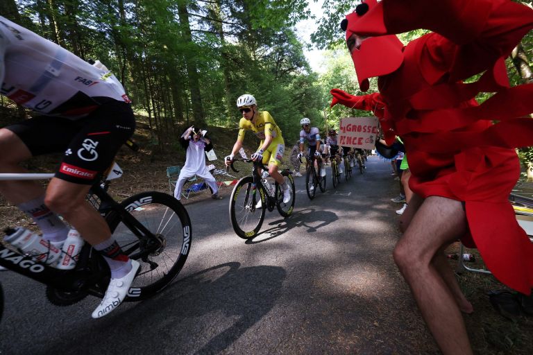 Cycling - Tour de France - Stage 9 - Malemort to Ussel - Malemort, France - July 12, 2026 UAE Team Emirates - XRG's Tadej Pogacar wearing the yellow jersey, UAE Team Emirates - XRG's Isaac Del Toro wearing the white jersey and Team Visma | Lease a Bike's Jonas Vingegaard wearing the polka-dot jersey in action as a spectator dressed in a costume cheers on during stage 9