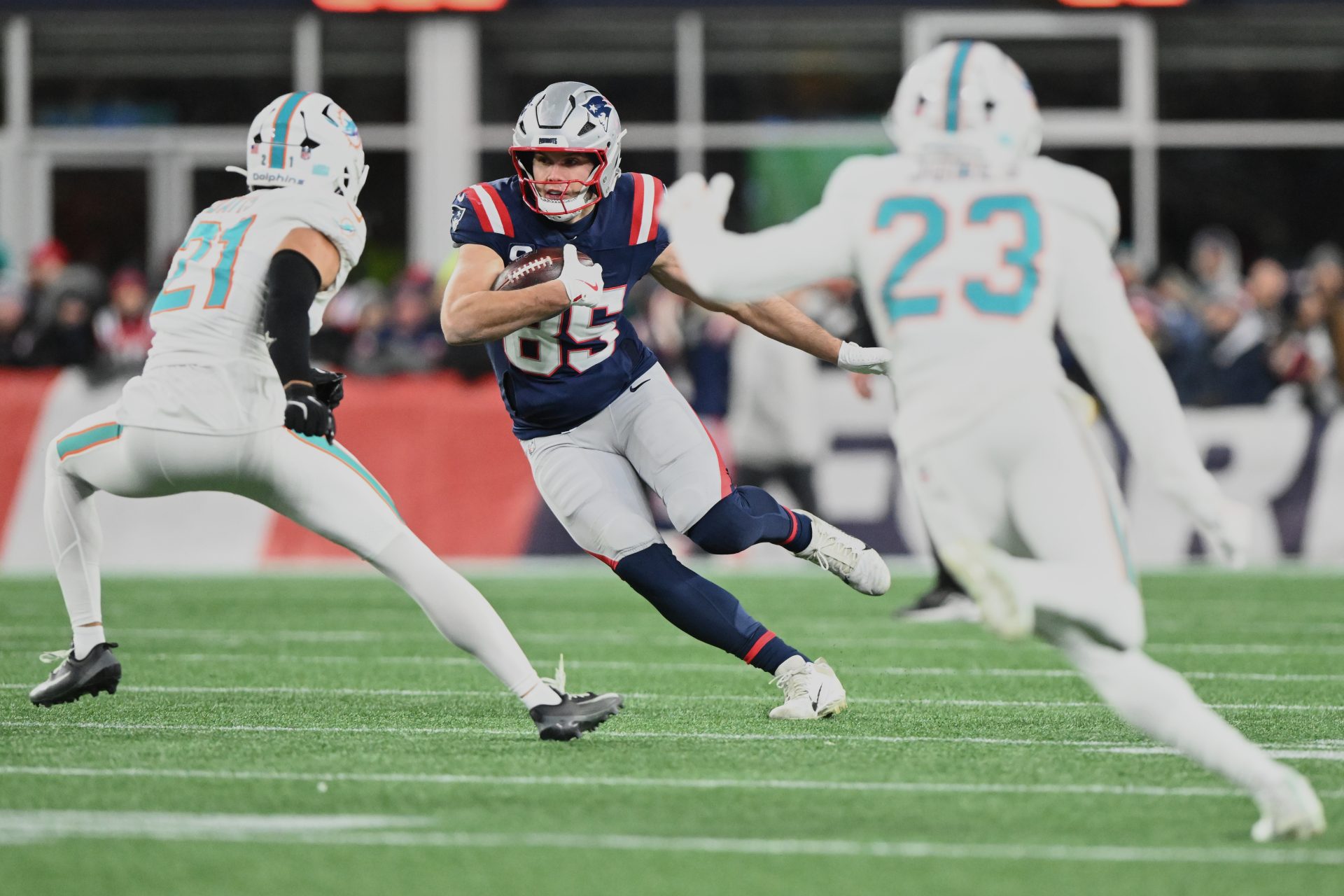 Jan 4, 2026; Foxborough, Massachusetts, USA; New England Patriots tight end Hunter Henry (85) runs after the catch against Miami Dolphins safety Ashtyn Davis (21) and cornerback Jack Jones (23) during the second quarter at Gillette Stadium.