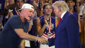 ESPN personality Pat McAfee, left, shakes hands with President Donald Trump during the Patriot Games held at Spire Academy, Aug. 11, 2026, in Geneva, Ohio.