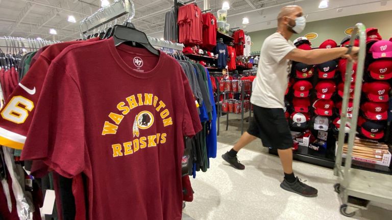 An employee passes Washington Redskins football shirts for sale at a sporting goods store in Bailey's Crossroads, Virginia, U.S., June 24, 2020. REUTERS/Kevin Lamarque
