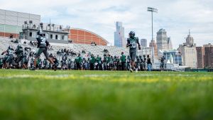 Detroit Cass Tech players warm up ahead of a high school football game against rival Detroit King at Cass Technical High School in Detroit on Friday, Sept. 25, 2026. The Detroit skyline is seen in the background.